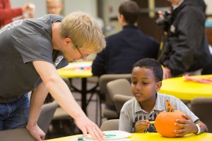 Seminary student Paul Flo, left, helps a child decorate a pumpkin in the Kids’ Corner as part of the 175th anniversary celebration. 