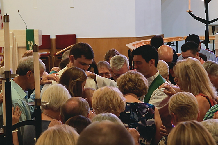 Rev. Steve Carretto, center, leads his congregation in prayer for Vicar Jacob and Rebecca Schultz and their son, Isaiah, on their last Sunday at St. Paul Lutheran Church.